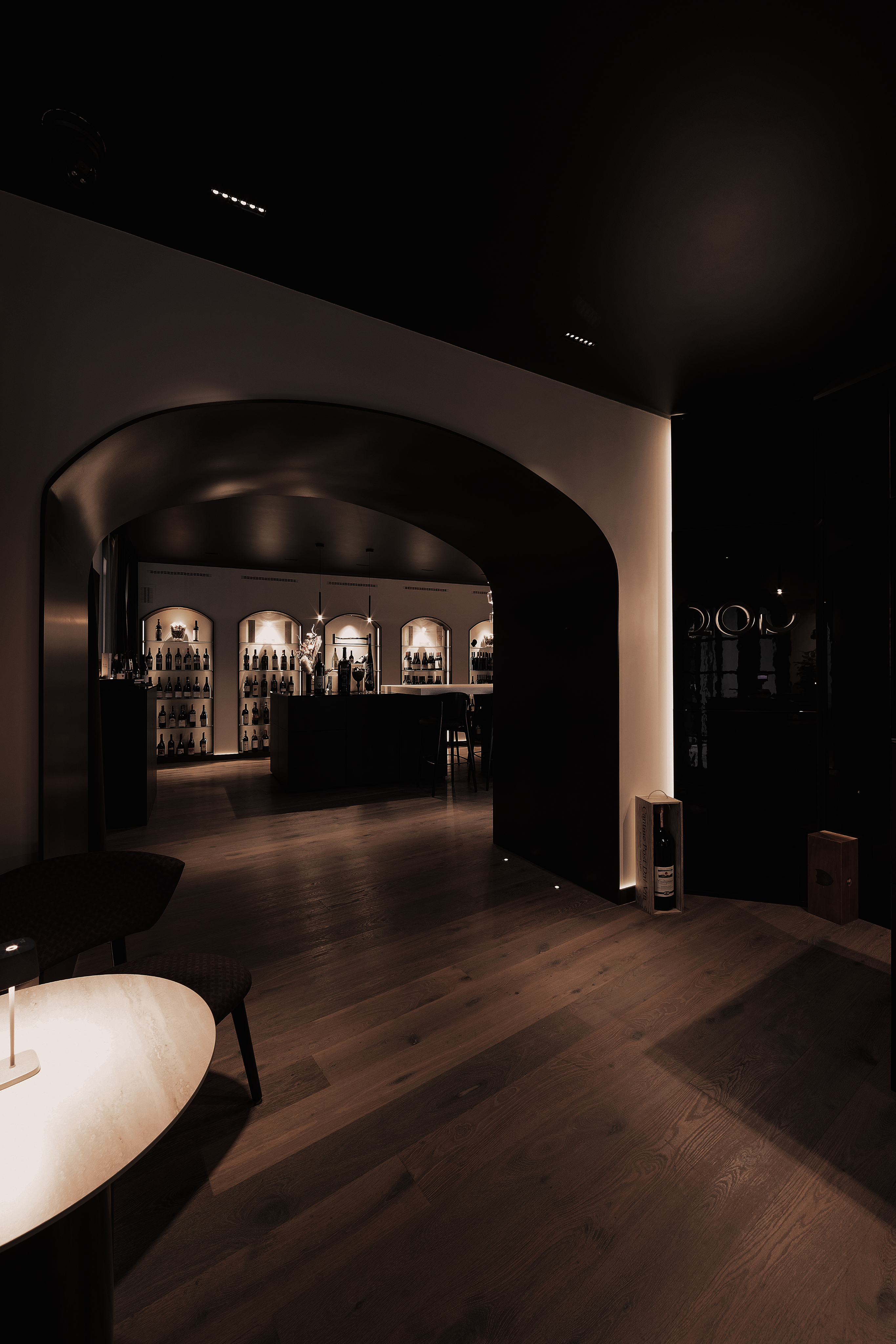 Ingresso della sala QOR con arcata scura, pavimento in legno e luci soffuse